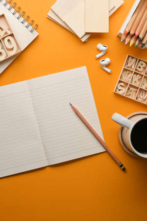 Top view of artist workspace with stationery, craft element and coffee cup on yellow tableの写真素材