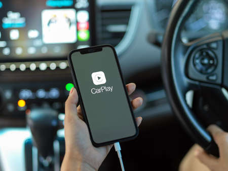 CHIANG MAI, THAILAND - MAY 11, 2020 : female hand holding smartphone with CarPlay application....