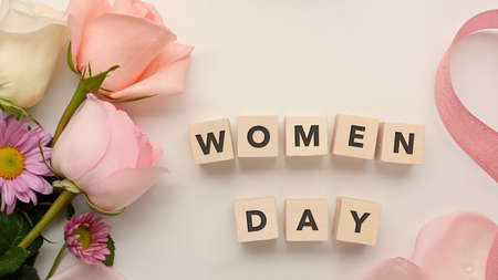 Dice with word "Women day" on white table background decorated with pink flowers and ribbonの写真素材