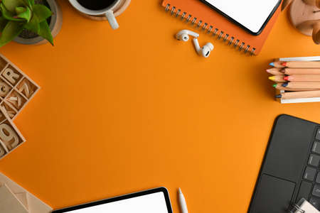 Top view of artist workspace with stationery, craft element, digital device and copy space on yellow...