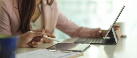 Cropped shot of businesspeople working together with digital tablets and paperwork in office room