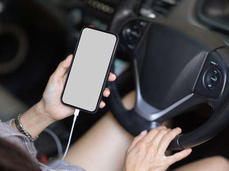 Close up view of female hand using mock up smartphone while driving a car at the traffic light