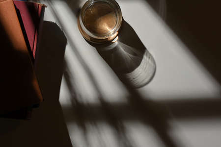 Top view of workspace with glass of water, books and copy space with sun light and shadowの写真素材