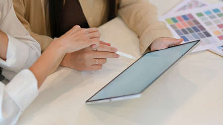 Close-up view of young female designer team working on their project together with tablet and laptop computer in workspaceの写真素材