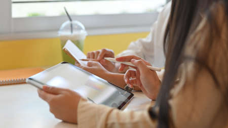 Group of businesswomen discussing their project together while using mock up tablet in meeting room