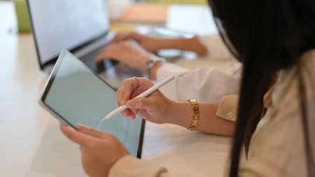 Side view of businesswoman working mock up digital tablet with stylus pen in office roomの写真素材