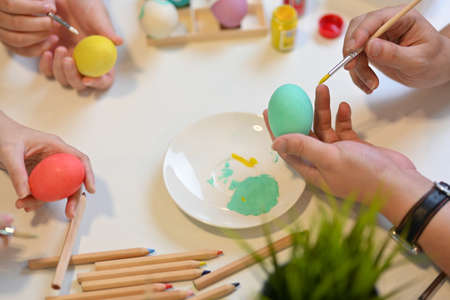 Top view of family preparing for Easter festival at home, painting on eggs