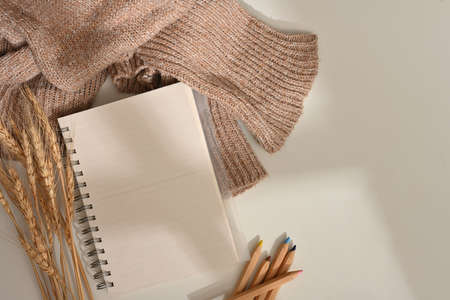 Creative flat lay workspace with notebook, coloured pencils, sweater and wheat decorated on the table, top viewの写真素材