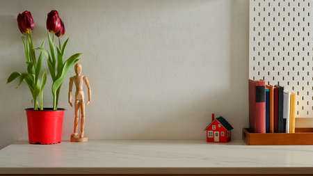 Stylish home interior design with tulips flower pot, books, decorations and copy space on the tableの写真素材