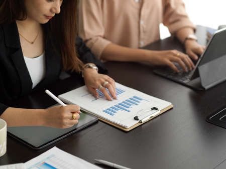 Cropped shot of businesswomen working together on business document and digital tablets in meeting...