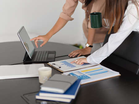 Cropped shot of two businesspeople working with digital tablet and business paperwork in meeting roomの写真素材