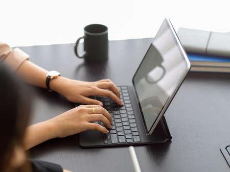 Side view of female hands typing on tablet keyboard on the table in meeting roomの写真素材