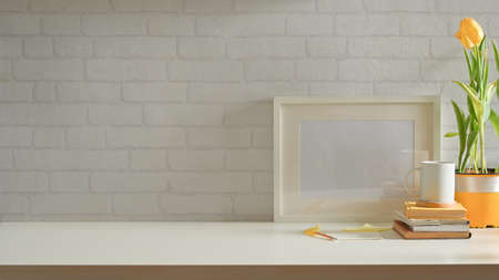 Stylish home interior design with workspace with mock up frame, plant pot, stationery and copy spaceの写真素材