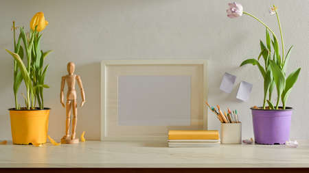 Cropped shot of stylish workspace with mock up frame, plant pots and stationery in living room