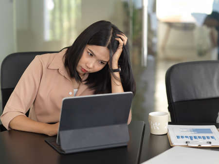 Portrait of businesswoman feeling upset while working with digital tablet in conference room