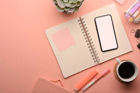 Top view of pink creative study table with smartphone, coffee cup and school elements, clipping path