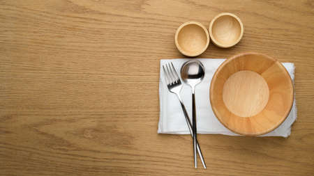 Mock up wooden bowls, table cloth and spoon and fork on white napkin, copy space, table setting backgroundの写真素材