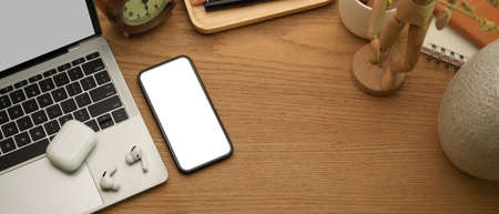 Top view of home office desk with smartphone, laptop, earphone and decorations on wooden table