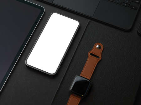 Cropped shot of dark creative flat lay workspace with smartphone smartwatch and accessories,...