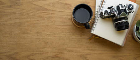 Creative flat lay workspace with notebooks, camera, coffee cup and copy space in home office room