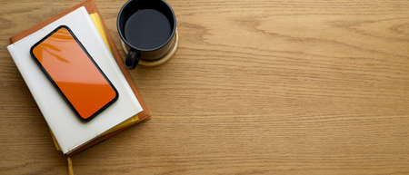 Top view of wooden table with copy space, mock up smartphone, notebooks and coffee cupの写真素材