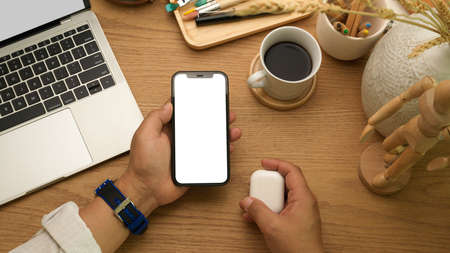 Overhead shot of businessman holding smartphone in his hand on home office desk, clipping path
