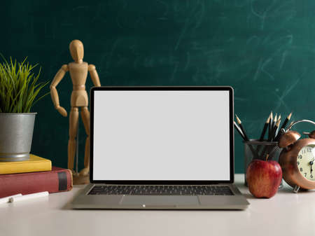 School elements, study table with mock up laptop, stationery, apple and decorations in chalkboard backgroundの写真素材