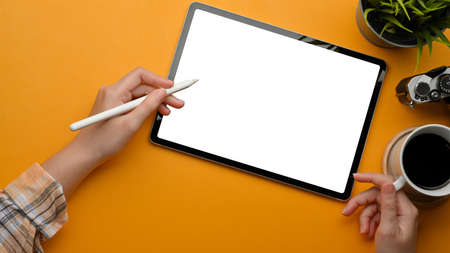 Top view of female freelancer hands using digital tablet with stylus pen on stylish workspace,...
