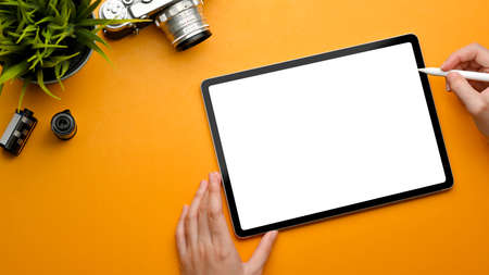 Top view of female hand with stylus pen using digital tablet on stylish workspace with camera and plant pot, clipping pathの写真素材