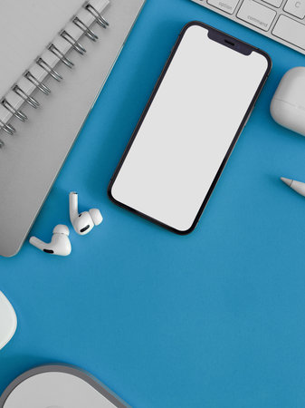 Creative flat lay workspace with smartphone, earphone, supplies and copy space on light blue background, clopped shot, clipping pathの写真素材