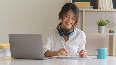 Portrait of happy female worker smiling while working with digital tablet in comfortable office room