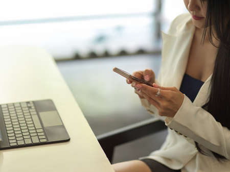 Cropped shot of businesswoman texting on smartphone while relax from work in office roomの写真素材