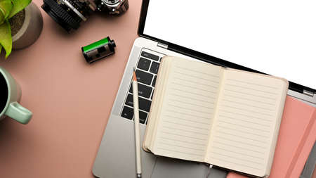Creative flat lay workspace with opened notebook, laptop and camera on pink table, clipping path,...