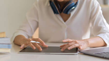 Close up view of female hands touching on digital tablet screen while working in home office room