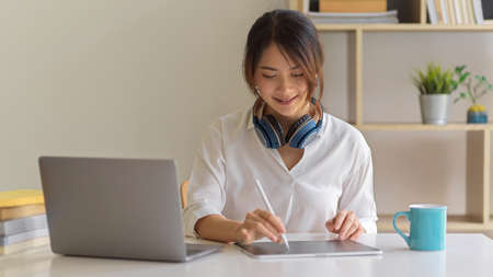 Portrait of female worker with headphone using digital tablet in comfortable home office roomの写真素材