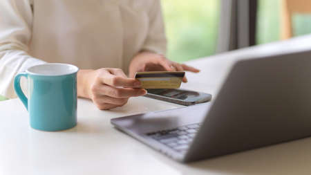 Cropped shot of female using internet banking application on smartphone to online payment with debit cardの写真素材