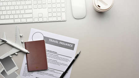 Travel concept, flat lay workspace with passport, insurance form, computer devices, travel items and copy spaceの写真素材