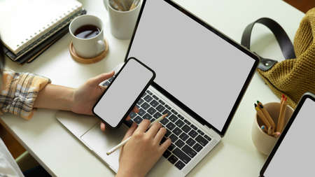Top view of female freelancer in Scott jacket working on smartphone and laptop include clipping path on home office deskの写真素材