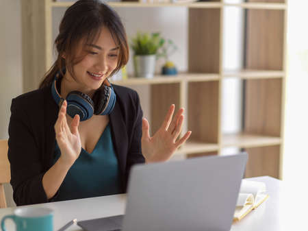 Work from home concept, businesswoman talking to her coworkers while video conference in home office roomの写真素材