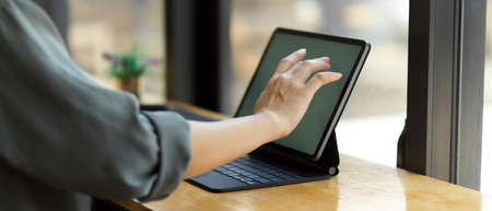 Side view of female hand touching on digital tablet screen on wooden bar in cafeの写真素材