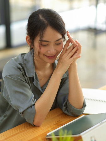 Portrait of friendly female office worker smiling while looking on tablet screen in offic eroomの写真素材