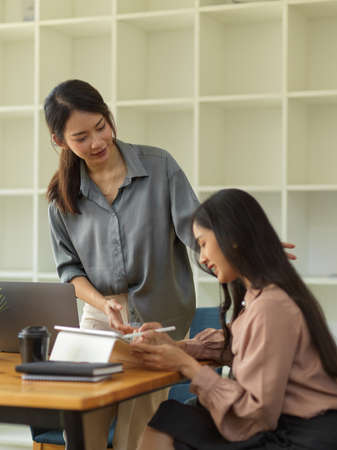 Quarter-length portrait of female senior giving advice to her underling while working in office roomの写真素材