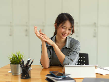 Portrait of happy female worker enjoying with her work in comfortable office roomの写真素材