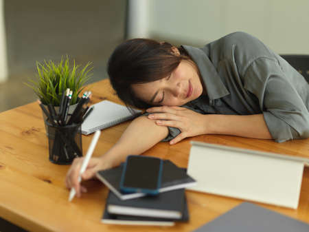 Portrait of female office worker take a nap when feeling tried while working in comfortable office roomの写真素材