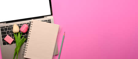 Top view of workspace with laptop, stationery, tulip flowers and copy space on pink table, clipping pathの写真素材