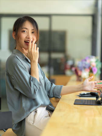 Portrait of young beautiful female feeling surprise while using digital tablet in coffee shopの写真素材