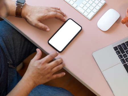 Top view of businessman using smartphone include clipping path screen on pink computer deskの写真素材