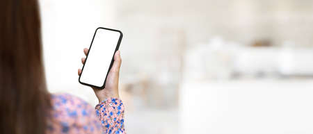 Close up view of female in beautiful spring dress hand holding smartphone in blurred background with copy space, clipping pathの写真素材