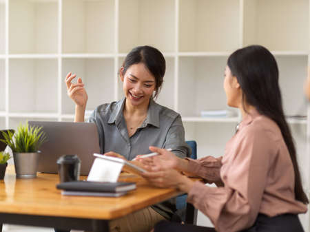 Half-length portraits of two businesswomen talking to each other while consulting on their projectの写真素材