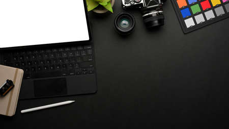 Dark creative workspace with digital tablet, camera, stationery, paint tools and copy pace, top view, clipping pathの写真素材